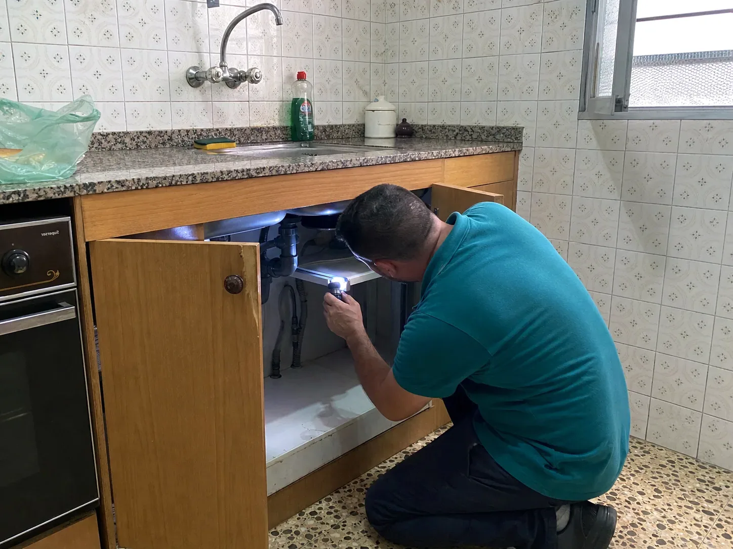 Técnico de PalauControl inspeccionando una cocina con linterna